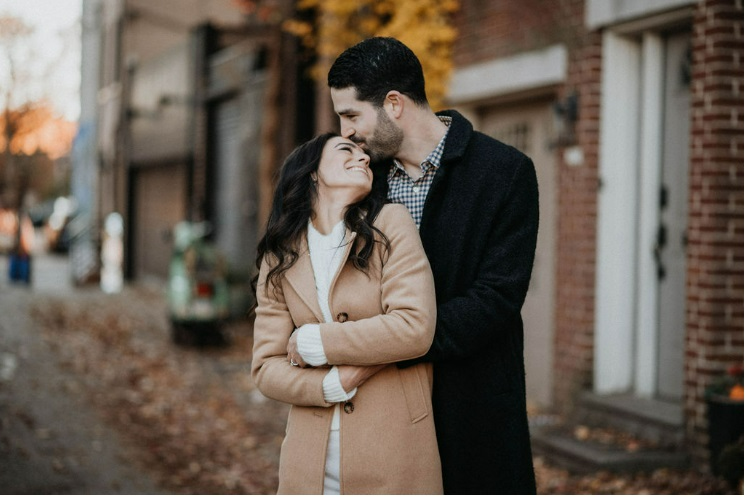 Couple embrace on city street at their winter engagement shoot.