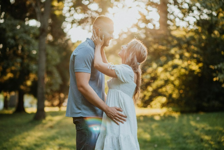 Couple embrace in an outdoor park for their summertime engagement shoot.