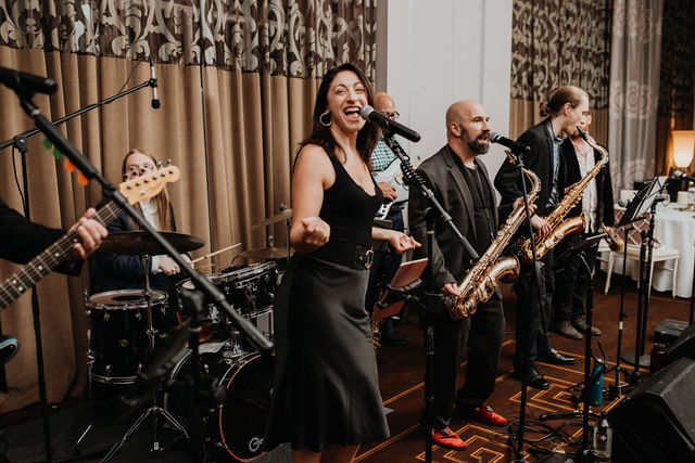 Woman smiling as she performs with her band at a wedding