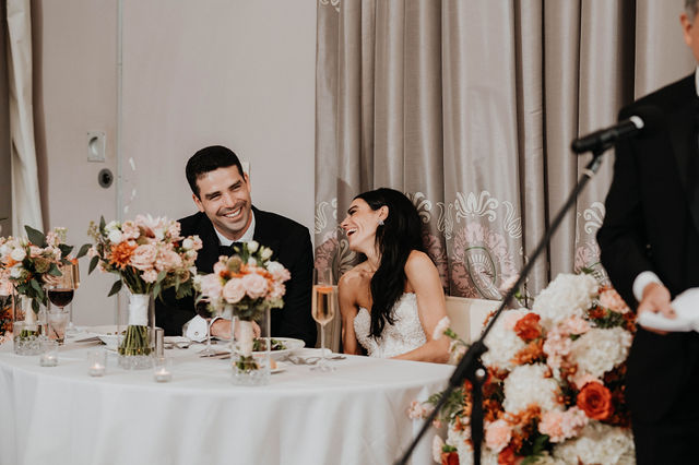 Couple smiling at a table decorated with professional floral arrangements